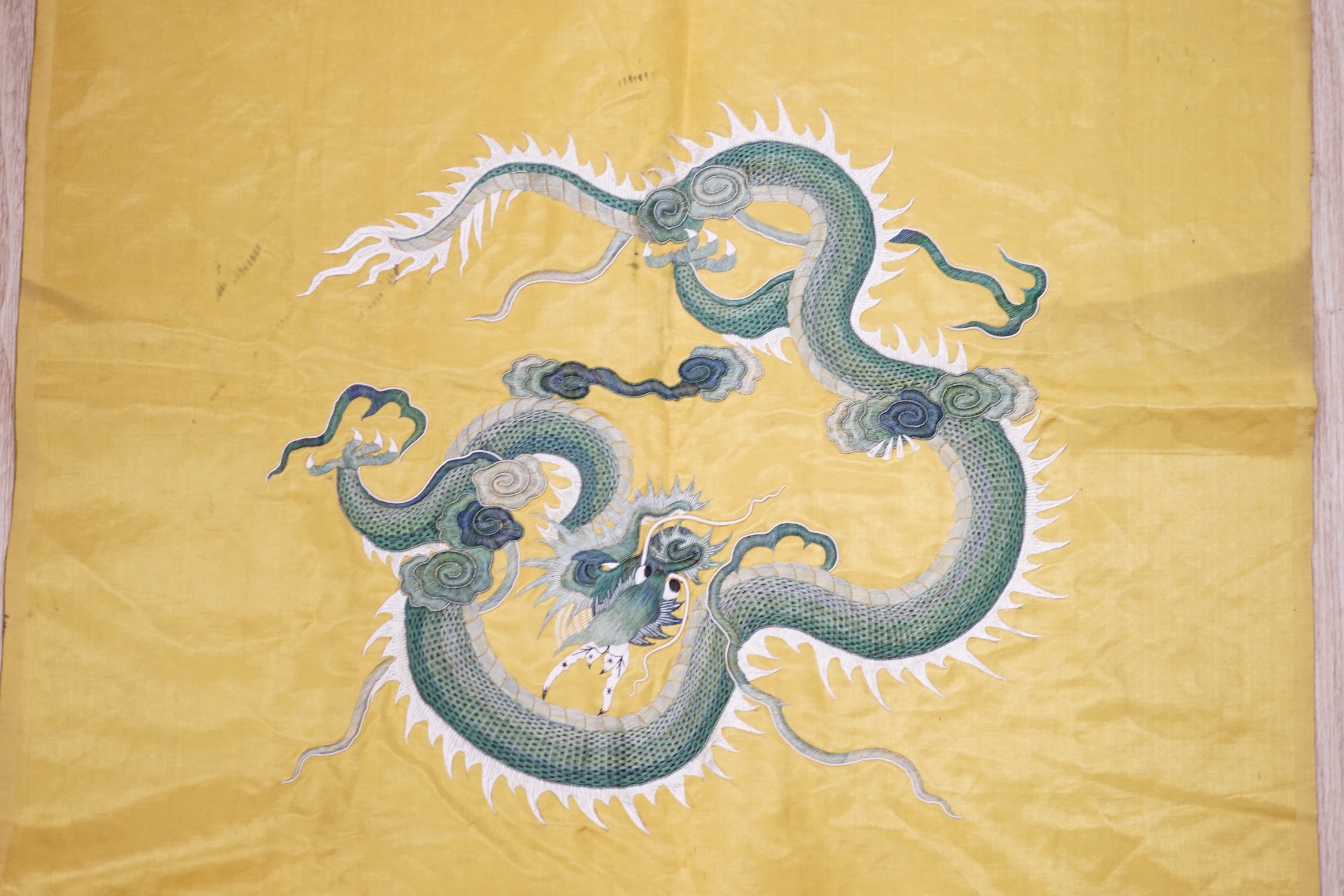 An early 20th century Chinese gold satin panel embroidered with two silk dragons, in couch work, 101cm x 60cm